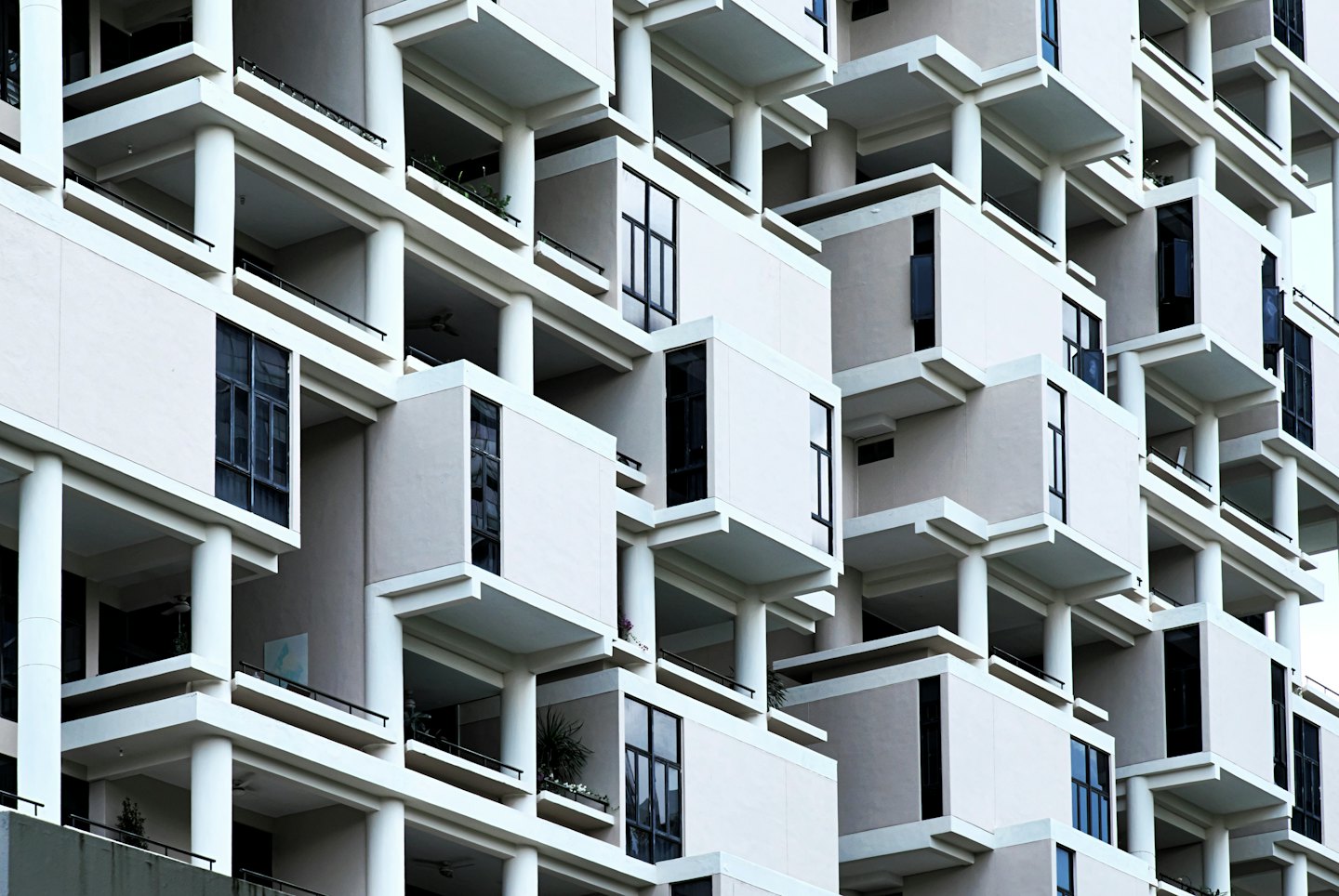 Modernes mehrstöckiges Wohnhaus mit geometrischen Balkonen und Grünpflanzen.
